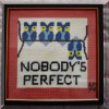 D17. “Nobody's Perfect” needlepoint. 